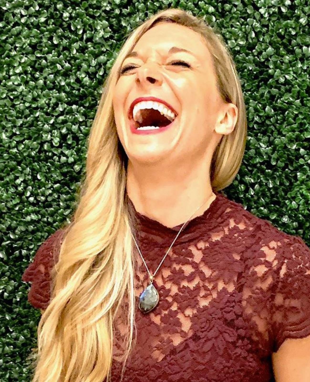 Blonde woman in fancy maroon shirt laughing